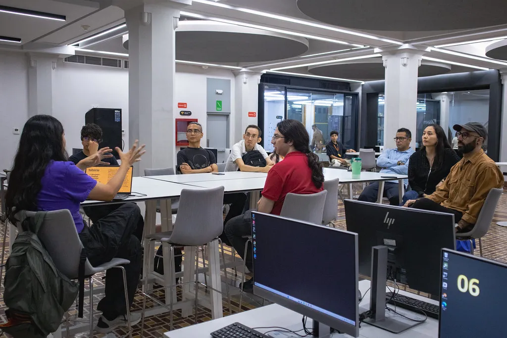 Mesa alta con ocho personas sentadas alrededor en el Área de Producción Digital del LabNL.