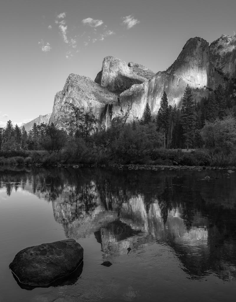 black and white photo of granite formations reflected in water of Yosemite valley