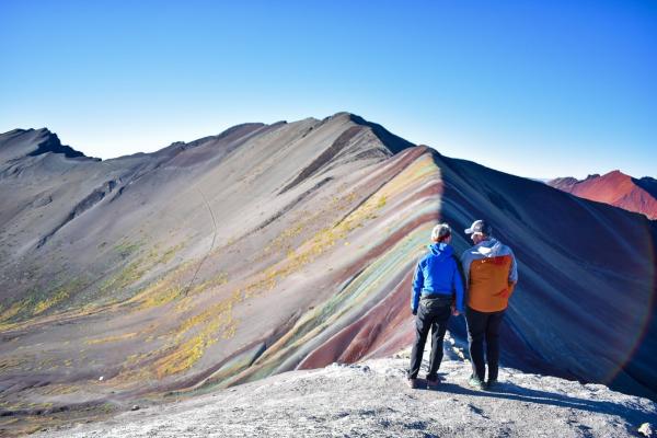 Two men looking out over Rainbow Mountain in Peru