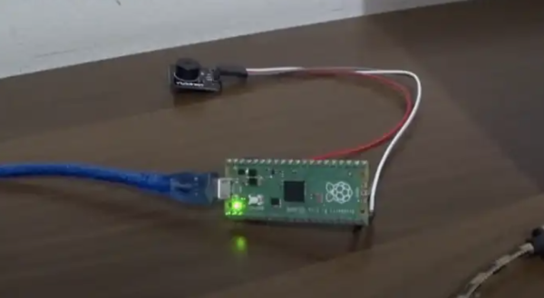Raspberry Pi pico on a desk attached to a tiny speaker