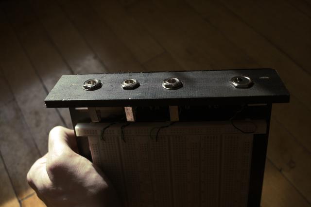 side of an electronics test bed showing three 1/4" jacks and a power connector