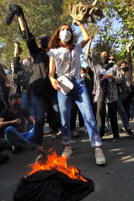 October 1, 2022: protesters set their scarves on fire while marching down a street in Tehran.