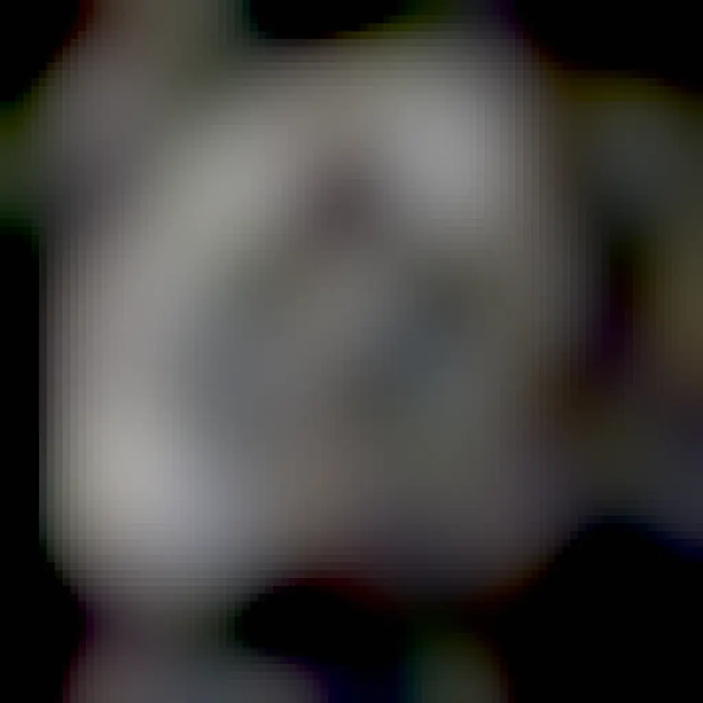 An oblong moon is shown that appears sponge like and features many odd craters. Close inspection shows that the bottoms of these craters are covered with a dark material.