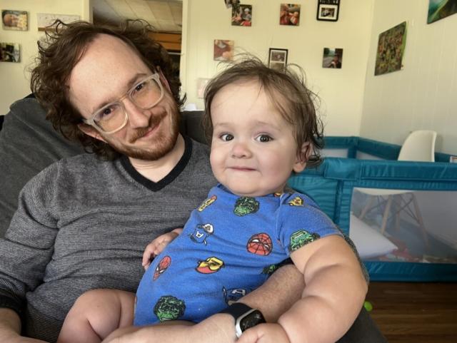 Ripley and I sitting on our couch. He’s wearing a Marvel super hero onesie and we both have crazy hair. 