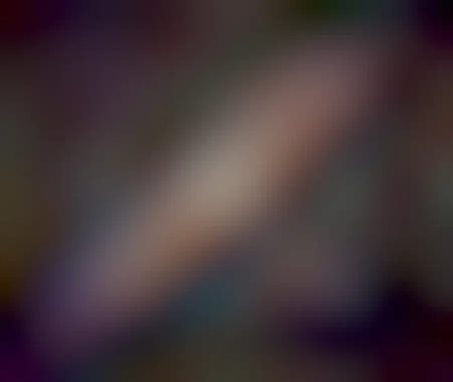 The Andromeda Galaxy is shown in great detail. Red nebulas, blue stars, and dark dust are all seen in a swirl around the galaxy's bright center.