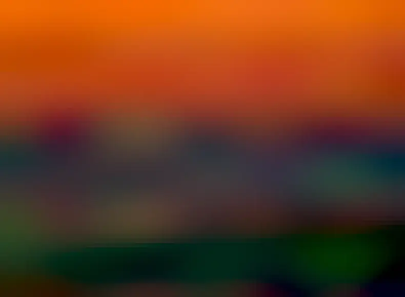 A distant sunset is seen between an orange sky and dark clouds. A close look at the Sun shows it is topped with several green strips, each known as a green flash.