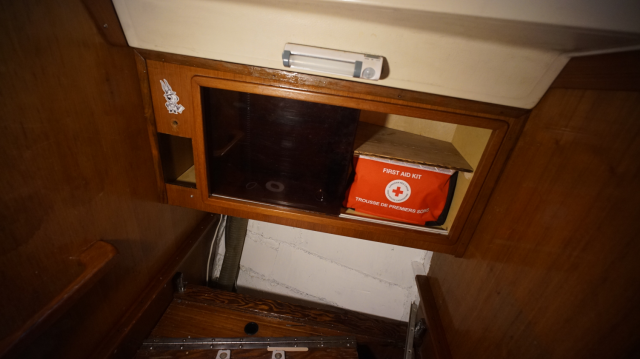 Head cabinet with a first aid kit on the shelf.