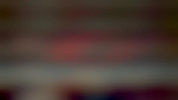 A large red ring is seen high above a landscape that has sparse clouds and a foreground building.