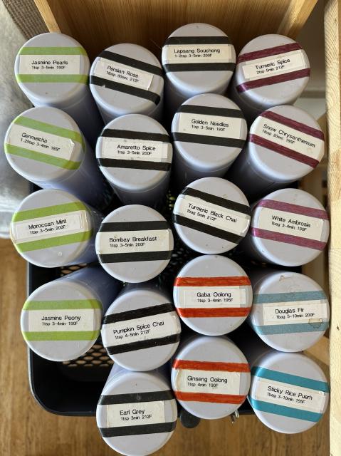 19 canisters of loose leaf tea labeled by color, temperature and brew time.