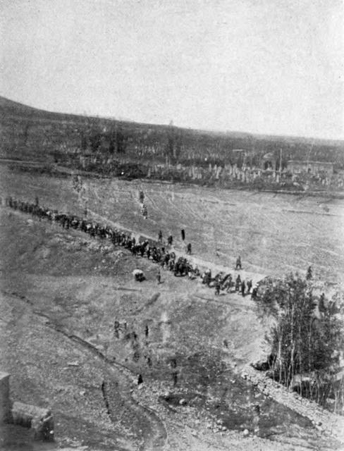 "A LONG LINE THAT SWIFTLY GREW SHORTER One of the most striking photographs of the deportations that have come out of Armenia. Here is shown a column of Christians on the path across the great plains of the Mamuret-ul-Aziz. The zaptieths are shown walking along at one side." -Ravished Armenia, p. 10. By Unknown author - File:Ravished Armenia.djvu p. 10 [1], Public Domain, https://commons.wikimedia.org/w/index.php?curid=18092075