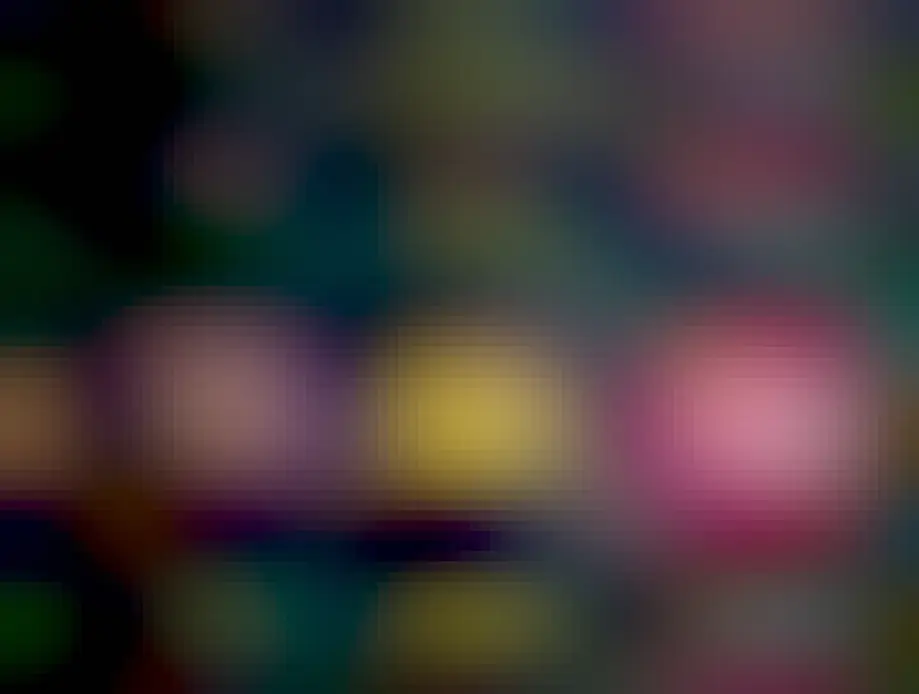 A black purse strap adorned with three metal pins:

1) Darkwing Duck pin that says "Let's Get Dangerous"
2) Powerline pin from the movie "A Goofy Movie"
3) A "Talkboy" pin from the movie "Home Alone 2", but instead of it being the typical grey and black, this pin is purple and pink. 