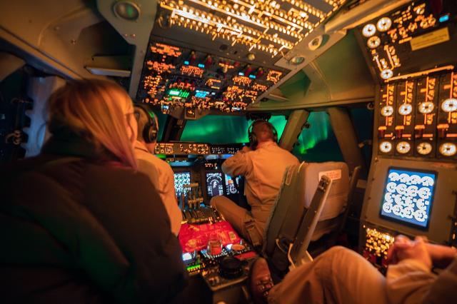 Picture yourself inside the flight deck of NASA's SOFIA Observatory. The pilots are in front of you with another person in the jump seat. Before you your view is full of dimly lit dials, while a green auroral glow is visible through the windows. 