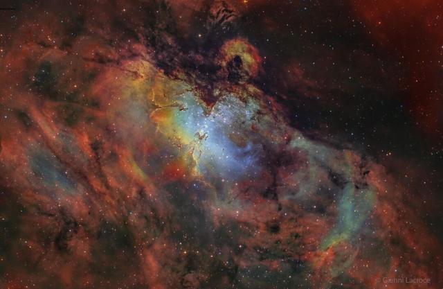 A deep image of the Eagle Nebula in many scientifically assigned colors. The area around the nebula appears red, but the center is blue with unusual pillars visible.