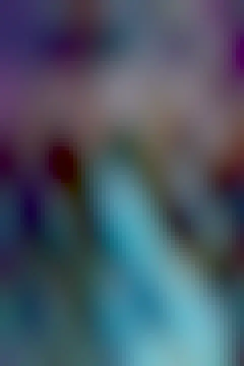 A shoreline glowing with blue bioluminescent plankton is shown, with a stand of trees in the distance. Above all is a starry sky which includes red nebulae and the central band of our Milky Way Galaxy.