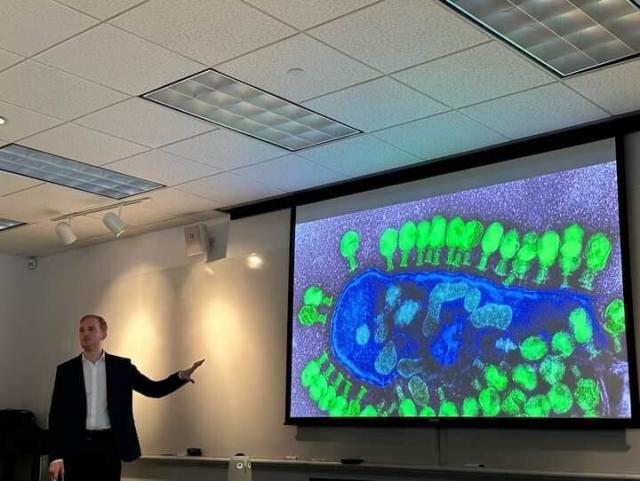 Me presenting a talk, showing a slide of a bacterium being infected by phages