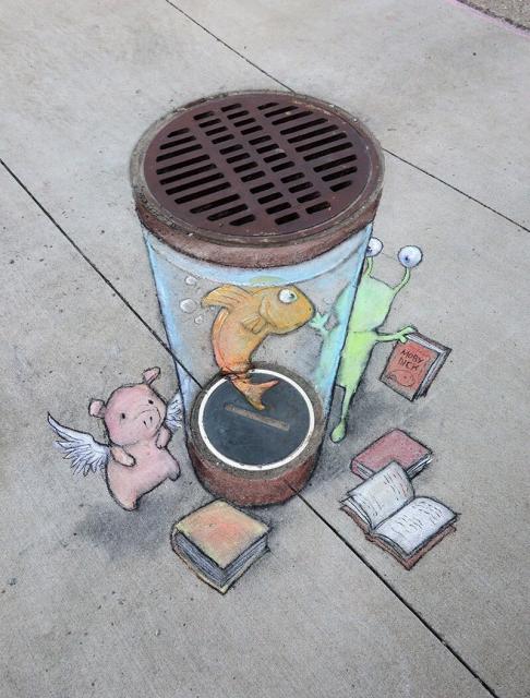Chalk art of an alien & pig with wings beaming up a goldfish by David Zinn.
