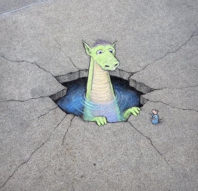 Chalk art of a dragon in a swimming  hole in the sidewalk by David Zinn.