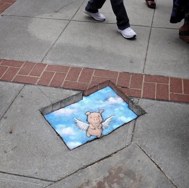 A pig appearing to fly through the sidewalk in chalk art by David Zinn