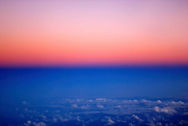 Aerial photo taken at dusk above the Amazonas. Distinct color separated by an horizontal line: reddish/pink above, blue below.