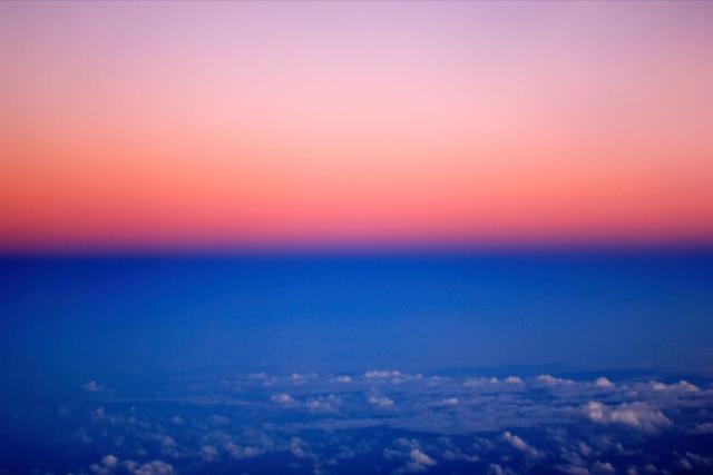 Aerial photo taken at dusk above the Amazonas. Distinct color separated by an horizontal line: reddish/pink above, blue below.