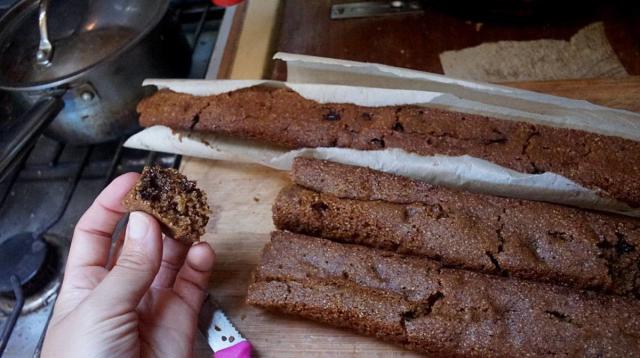 some chocolate chip cake in the shape of a tube with a hand holding a slice