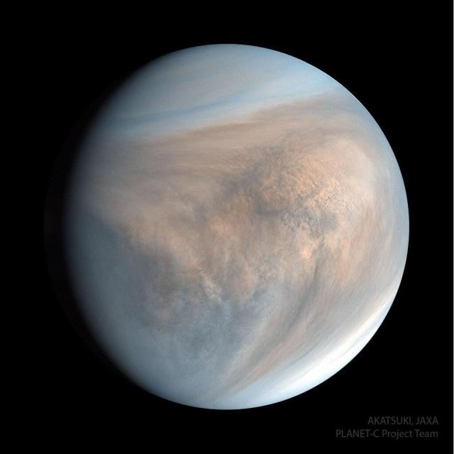 Planet Venus is pictured in ultraviolet light. The spherical planet appears circular in tan colors with hints of blue. Complex cloud patterns are evident.