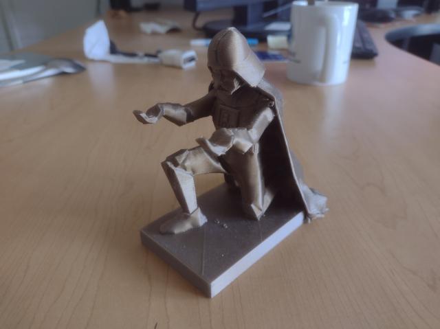 A pen holder shaped like Darth Vader kneeling down and holding his arms up
