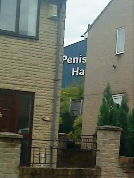 A building with the sign on it partially obscured by two other buildings, so that all that's visible is "Penis Ha"