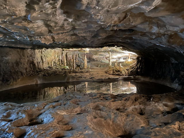 A grotto with water reflecting stalactites and stalagmites 