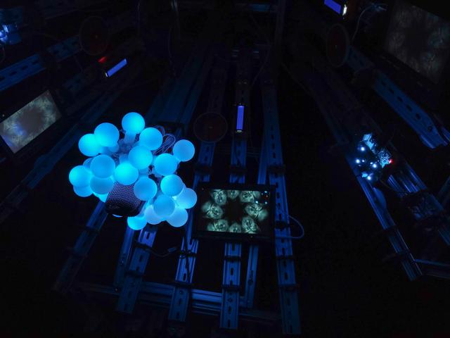 Its central "pistil" has globe-shaped LEDs as "pollen." A small display shows a face splayed out eight times in a ring, forming a creepy circle.