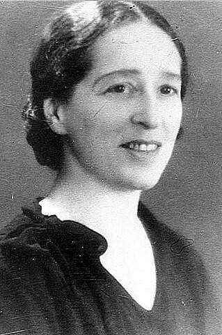Formal black and white photograph of Elisabeth Wollman. Her hair is in a low bun, and she's smiling.