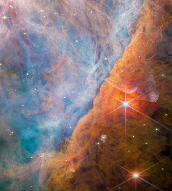 This image taken by Webb’s NIRCam (Near-Infrared Camera) shows a part of the Orion Nebula known as the Orion Bar. It is a region where energetic ultraviolet light from the Trapezium Cluster — located off the upper-left corner — interacts with dense molecular clouds. The energy of the stellar radiation is slowly eroding the Orion Bar, and this has a profound effect on the molecules and chemistry in the protoplanetary disks that have formed around newborn stars here.

Within this image lies a young star system known as d203-506, which has a protoplanetary disk. Astronomers used Webb to detect a carbon molecule known as methyl cation in that disk for the first time. That molecule is important because it aids the formation of more complex carbon-based molecules.

Credits
Image
ESA/Webb, NASA, CSA, M. Zamani (ESA/Webb), PDRs4ALL ERS Team