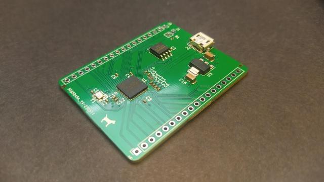 A small rectangular PCB board. THe board has a USB socket and numerous larger components, an RP2040, a p0wer regulator and more. There are also tiny 0402 package capacitors and resistors. 