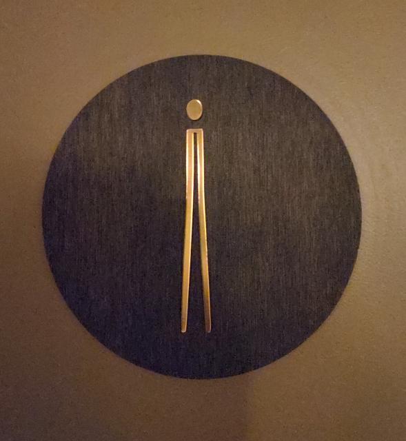 Bathroom sign for the female bathroom, consisting of a thin line and a circle for the head.