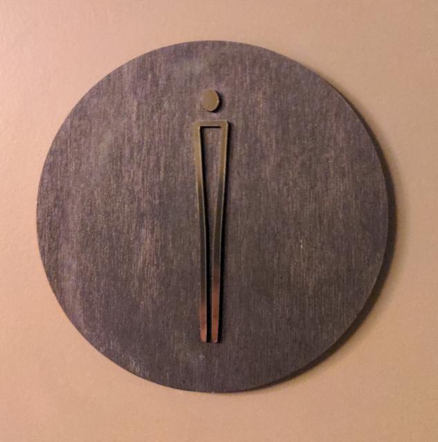 Bathroom sign for the male bathroom, consisting of a thin line and a circle for the head.