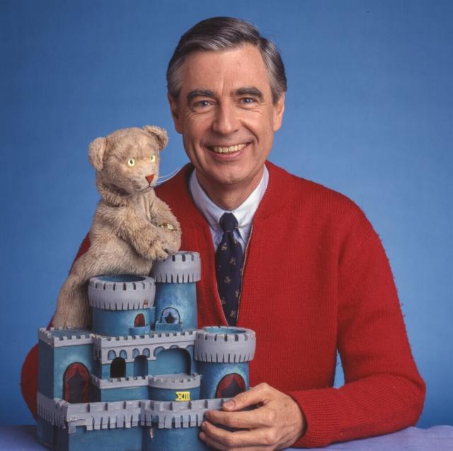 Fred Rogers shows a Daniel Tiger puppet and a replica of King Friday's castle.