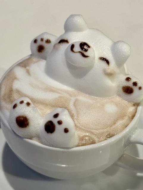 3D latte art of a bear bathing in a cup.