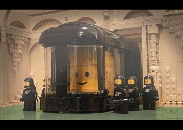 six black classic LEGO spacemen surround a huge black frames aquarium like tank. Inside is one big LEGO head.