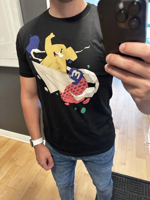 New mastodon project swag: a very happy Mastodon sailing around on a paper airplane on a tshirt