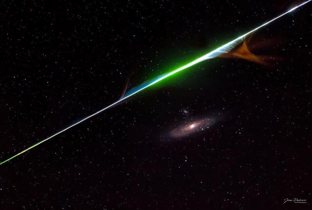 A color meteor streak is seen above the Andromeda spiral galaxy.