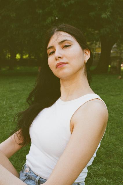 Up close portrait of a beautiful woman with dark hair in a white tank top in a park