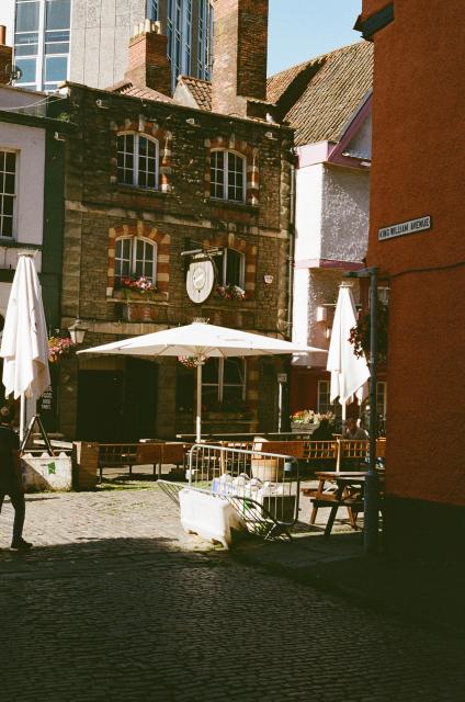 An old terraced building housing a restaurant. Sunlight falls on the street from the side.