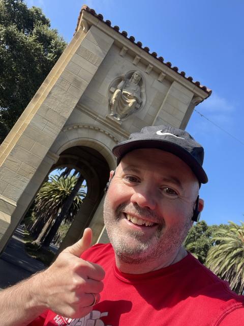 Sanford University entrance arch, runner with thumbs up