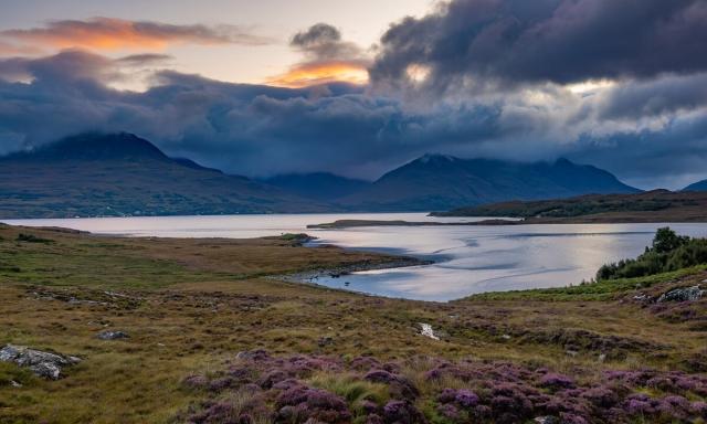 Highland landscape at dawn. Dark clouds and still sea.