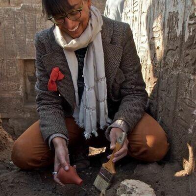 Shyama is excavating a goat's skull dating to the Medieval Period. The walls are covered in hieroglyphics.
