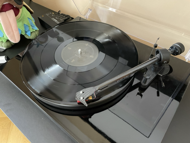 A vinyl record placed within a record player. 