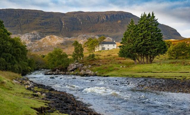 Rapidly flowing river, vertical cliff behind.