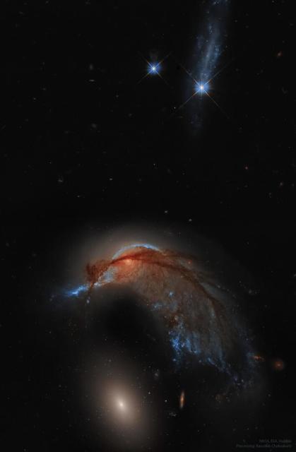 A starfield with two bright stars at the top of the frame and two galaxies at the bottom. The upper galaxy is a spiral galaxy and has an appearance reminiscent of a hummingbird. The lower galaxy is a featureless elliptical galaxy.