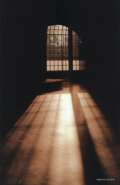 Photo of sunlight shining into a room, casting a long shadow of the window on the dark floor.