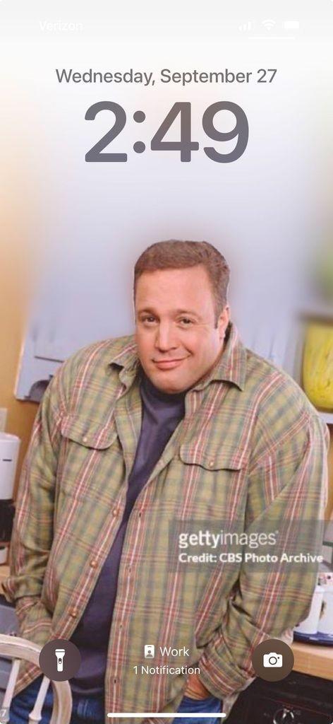 Screenshot of an iPhone lock screen where the wallpaper is a meme of Kevin James smirking